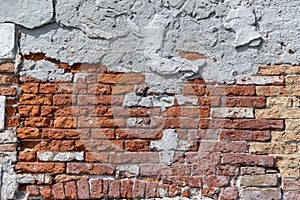 Plaster peeling from an old red brick wall. Worn out building in Venice