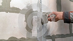 Plaster the wall with a putty knife.Internal construction and finishing works.The Builder puts plaster on the wall.Hand