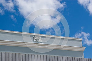 Plastered wall of a building with the number 1951 on a background of blue sky with clouds