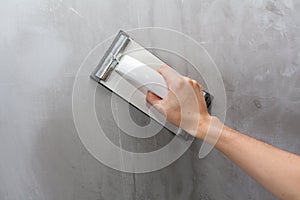 Plasterer erases irregularities on the wall with trowel.