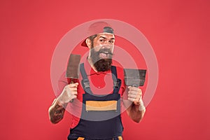 Plasterer hipster builder in cap red background. Interior designer. Bearded man worker with plastering tools