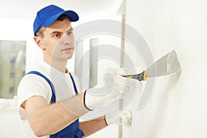 Plasterer with putty knife at wall filling