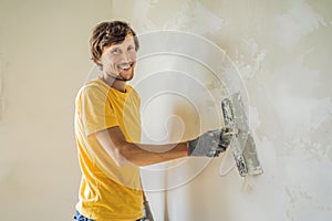 Plasterer home improvement handyman worker with putty knife working on apartment wall filling