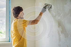 Plasterer home improvement handyman worker with putty knife working on apartment wall filling