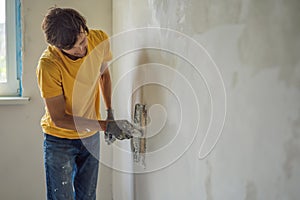 Plasterer home improvement handyman worker with putty knife working on apartment wall filling