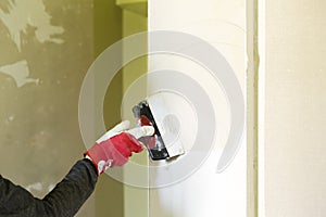 Plasterer home improvement handyman worker with putty knife working on apartment wall filling. Home renovation concept