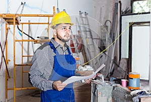 Plasterer is looking on the project of work for the object.