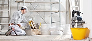 Plasterer man construction worker work with tool box wear gloves, hard hat and protection glasses at interior building site with