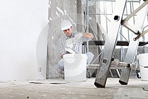 Plasterer man at work, take the mortar from the bucket to plastering the wall of interior construction site wear helmet and