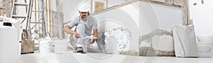 Plasterer man at work, take the mortar from the bucket with trowel to plastering the wall of interior construction house site and