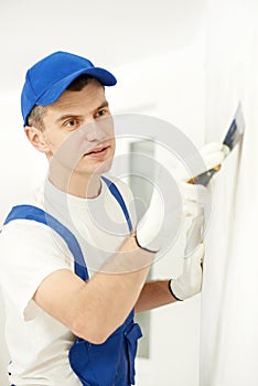 Plasterer with putty knife at wall filling photo