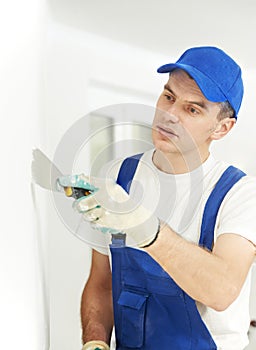 Plasterer with putty knife at wall filling photo