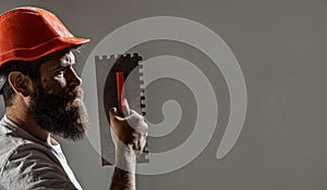 Plasterer renovating wall. Profile of bearded builder. Worker with plastering tools. Renovating house concept. Builder