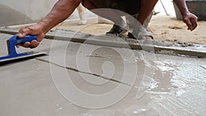 Plasterer smoothing floor surface with screeder