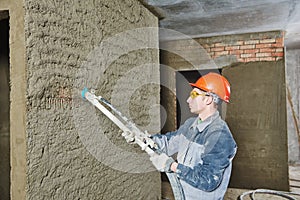 Plasterer spraying plaster on wall