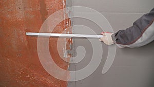 Plasterer using screeder smoothing putty plaster mortar on wall. Smoothing out putty on the wall. photo