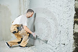 Plasterer using screeder smoothing putty plaster mortar on wall photo