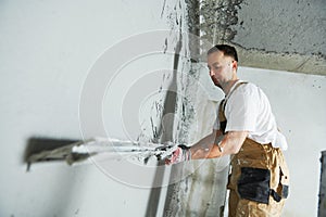 Plasterer using screeder spraying putty plaster mortar on wall