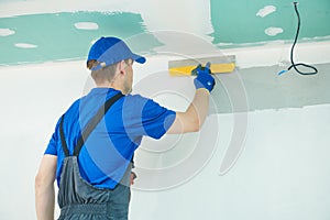 Refurbishment. Plasterer worker spackling a wall with putty photo