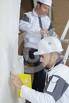 plasterers applying plaster on wall with spatula