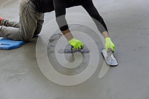 During the plastering of concrete to cement floor, a masonry worker holds a steel trowel in his hand as he smoothes the