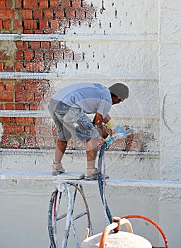 Plastering facade with injected mortar, mason working