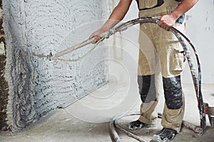 Plastering the interior wall with an automatic spraying plaster pump machine