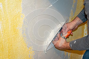 Plastering a wall with plaster in a house with a plaster knife and putty knife