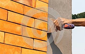 Plastering wall with putty-knife. Close up image man holding putty-knife on cement wall.