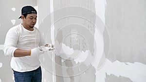 Plasterwork and wall painting preparation. Asian male applying filling drywall patch