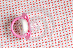 Plastic baby soother pacifier on pink blanket