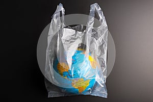 Plastic bag Earth world globe  on black background. Saving the planet Earth from plastic bags concept