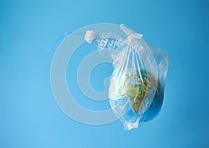 A plastic bag with a globe and a plastic bottle on a blue background. Concept: planetary plastic pollution