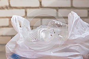 A plastic bag lies at the brick wall with used polypropylene utensils