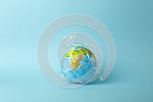 Plastic bag pollution concept. Earth globe in a plastic bag on a colored background. Plastic and waste pollution oceans, nature