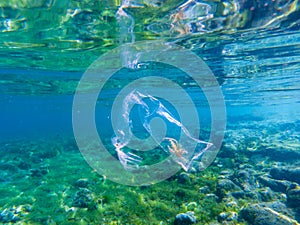 Plastic bag with seaweed inside in blue sea water, underwater photo. Tropical sea with plastic trash. Ecology problem