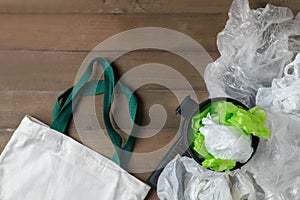 Plastic bags in bin and canvas tote bag on wood