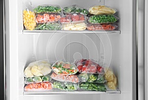 Plastic bags with different frozen vegetables in refrigerator