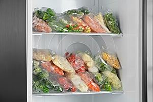 Plastic bags with frozen vegetables in refrigerator