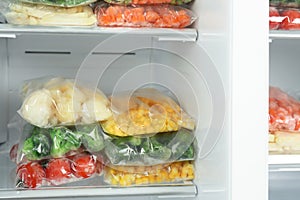 Plastic bags with frozen vegetables in refrigerator