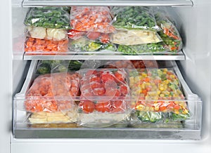 Plastic bags with frozen vegetables in refrigerator