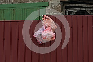 Plastic bags with garbage hang on the red metal wall