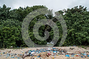 Plastic bags and plastic bottles and all sorts of garbage  left at the beach near ocean at the tropical island