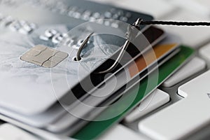 Plastic bank cards and fishing hook on white computer keyboard