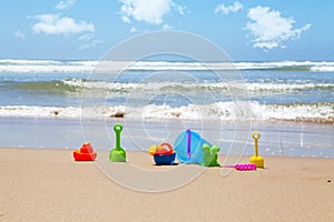 Plastic beach toys on beach with sea in background