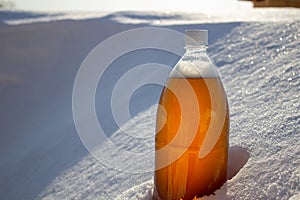 Plastic beer bottle in the snow in winter in nature, beer background