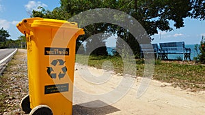 Plastic bin yellow for Garbage Waste at asphalt road in asian tropical coast. Thailand, Koh Chang. Garbage waste bin