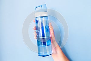 Plastic blue bottle for water in a female hand