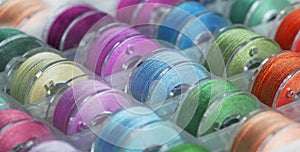 Plastic bobbins for a sewing machine with brightly colored threads in a storage box