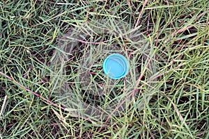 A plastic bottle cap on green grass background, environment concepts